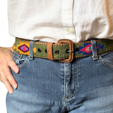 Person wearing a colorful belt with a white shirt and blue jeans.