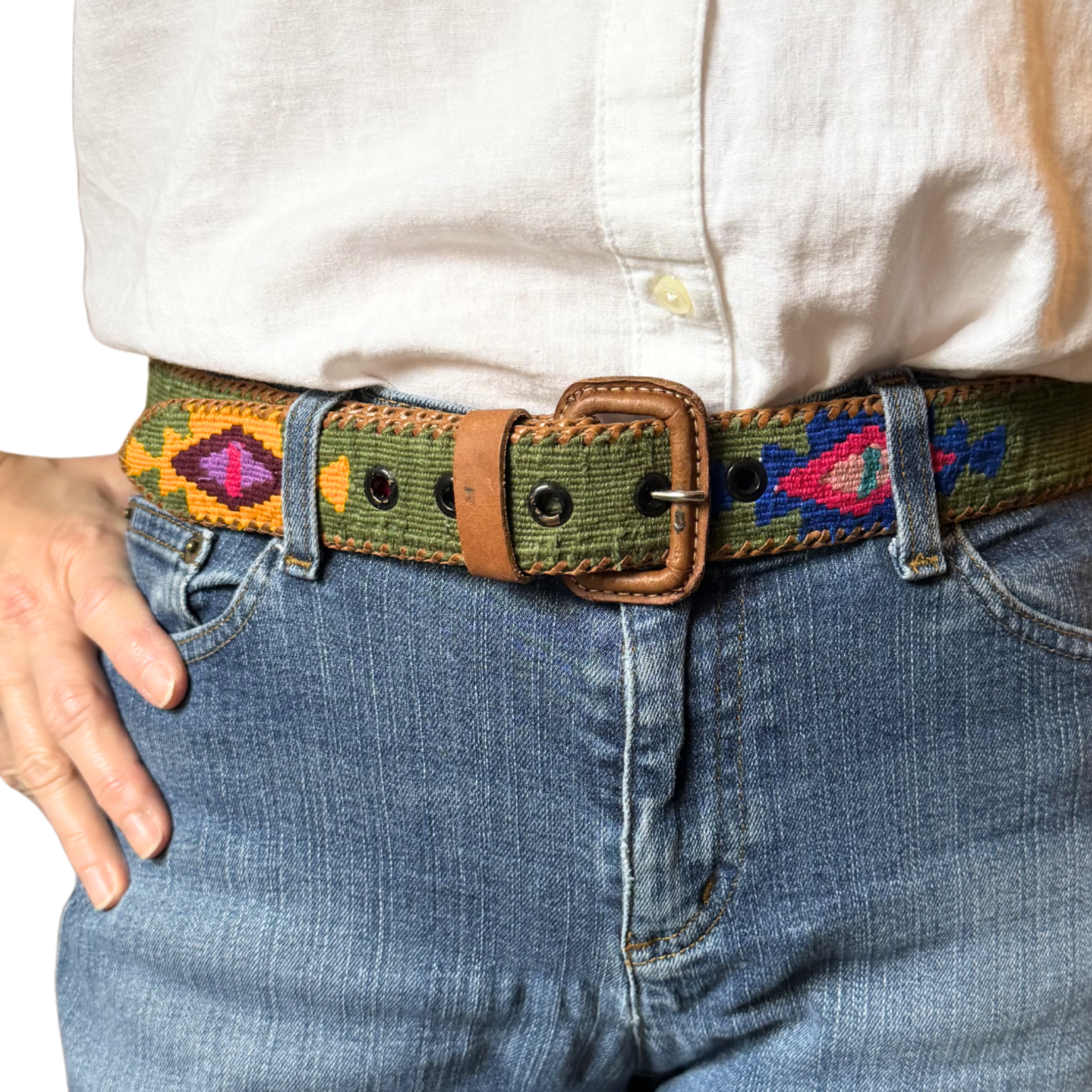 Person wearing a colorful belt with a white shirt and blue jeans.