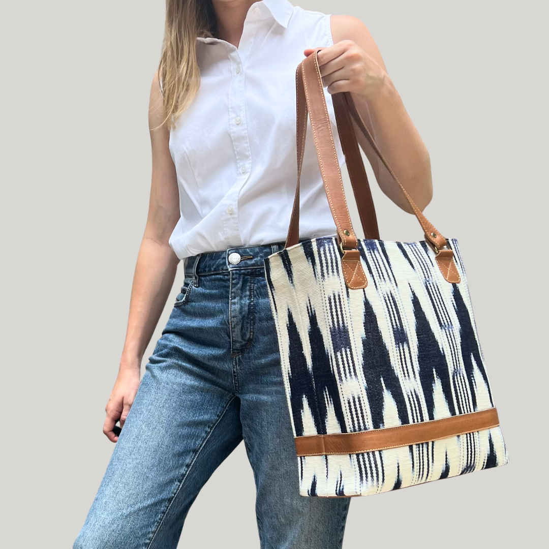 Model holding Intertwined: Handmade for Good's navy and white Jaspe Structured Tote.