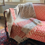 Patterned wool blanket draped over a red and white chair in a room with a window.