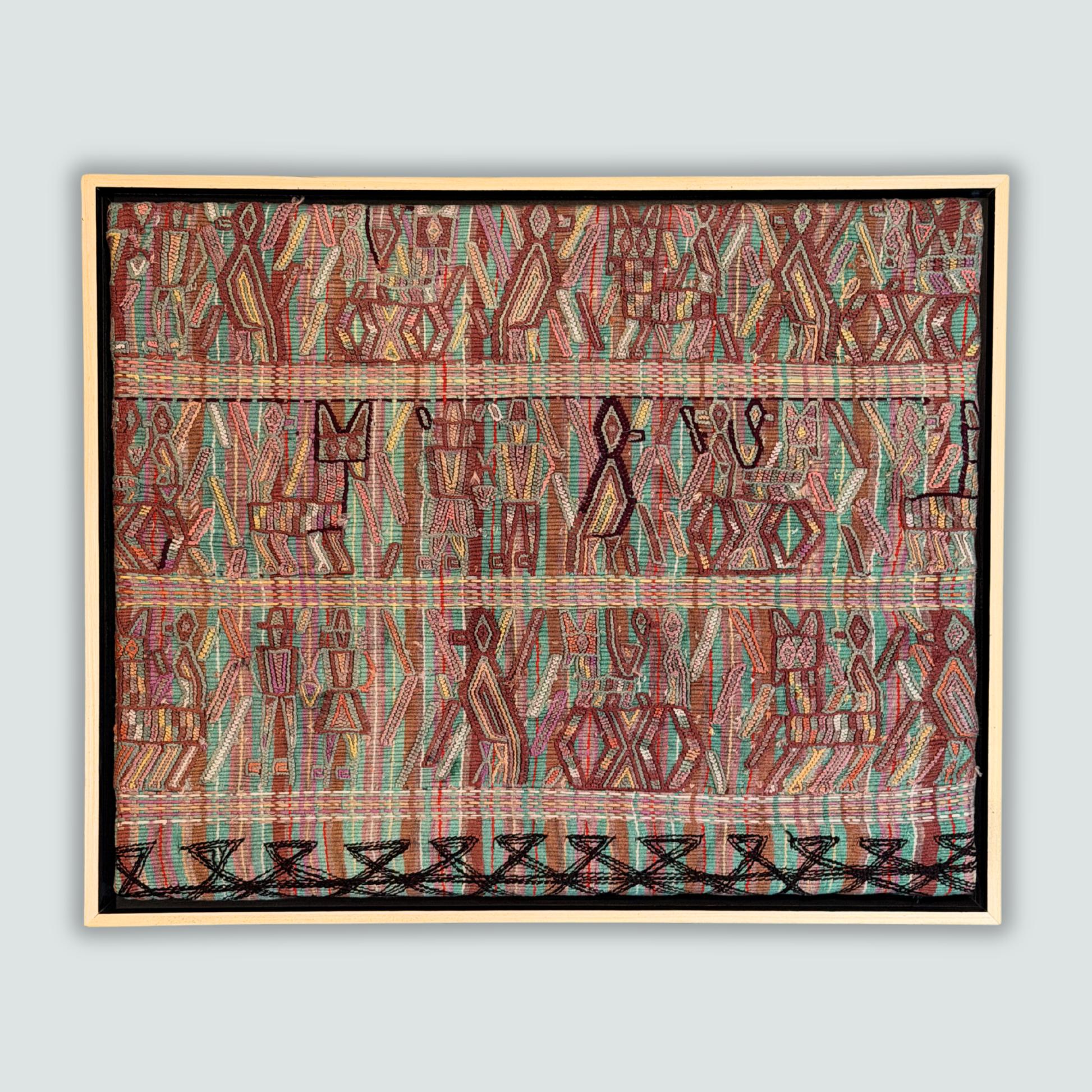 Framed handwoven textile with geometric pattern on a light gray background