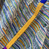 Close-up of a colorful striped woven textile with diagonal yellow trim and blue and purple edging.