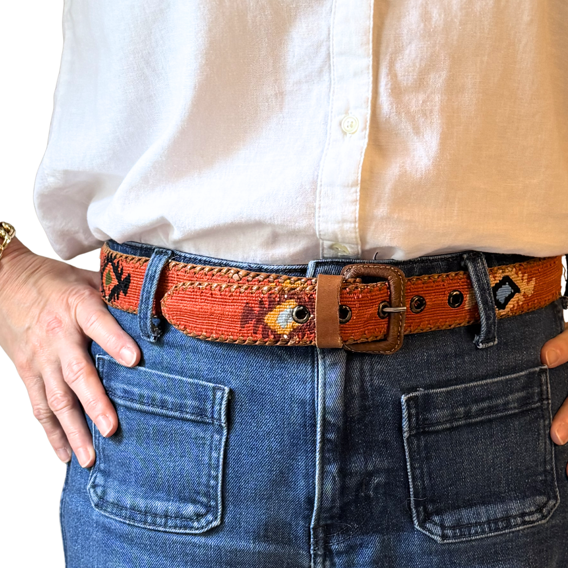 Person wearing a white shirt, orange belt with a pattern, and blue jeans.