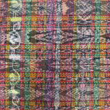 A close-up of a multicolor plaid fabric with vertical stripes in shades of purple, green, orange, pink, yellow, and black.