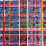 A close-up of a multicolor plaid fabric with vertical stripes in red, orange, yellow, blue, purple, and white over a dark base.