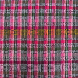 A close-up of a woven textile with a multicolor plaid pattern featuring pink, green, purple, and black stripes with geometric woven motifs.