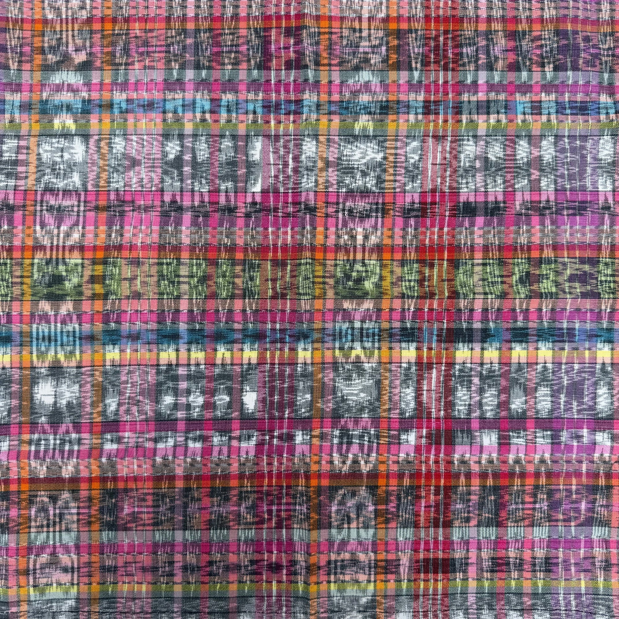 A close-up of a multicolor plaid fabric pattern with pink, purple, orange, blue, green, and gray intersecting stripes and distressed texture.