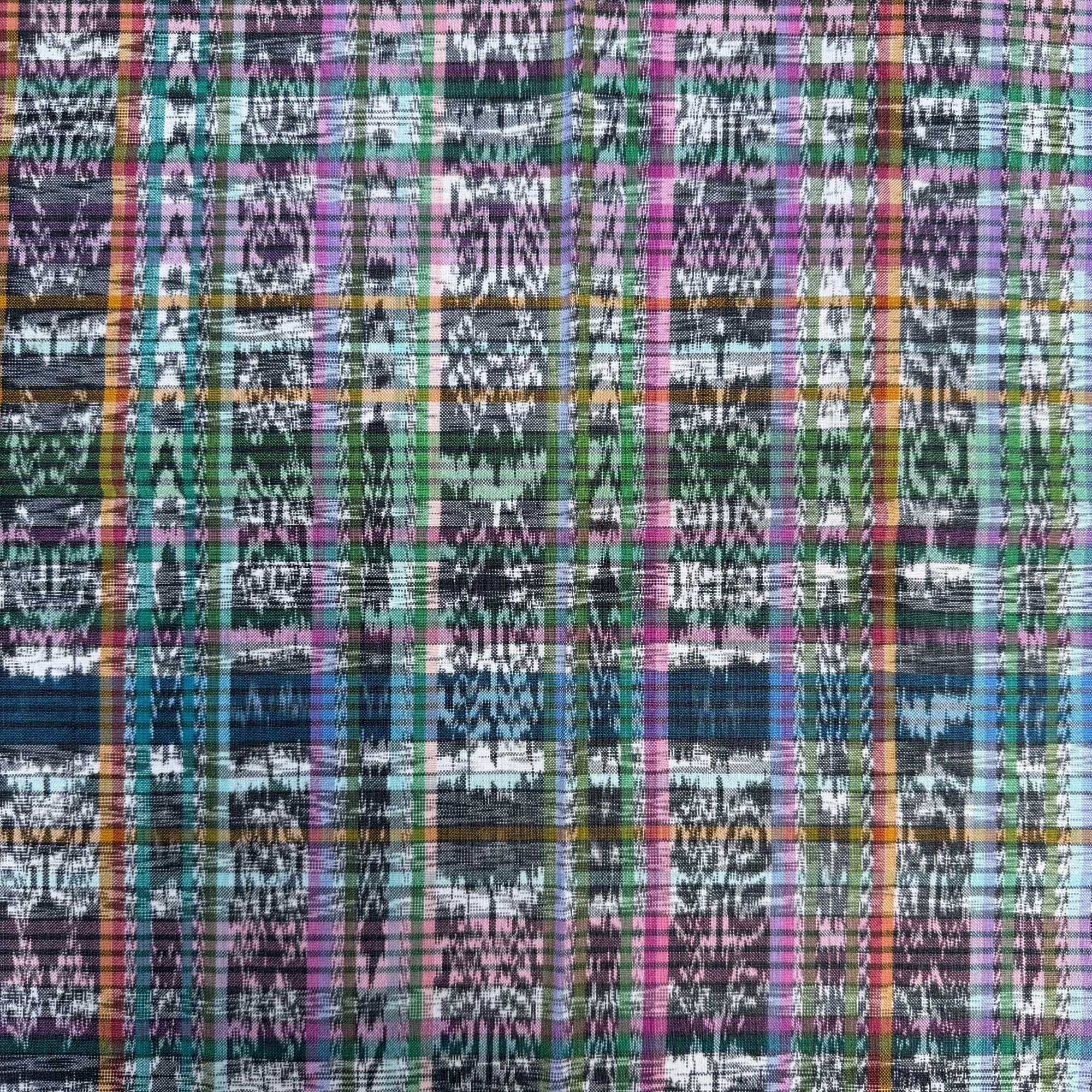 A close-up of a woven fabric with a multicolor plaid ikat pattern featuring shades of blue, green, pink, orange, and black.