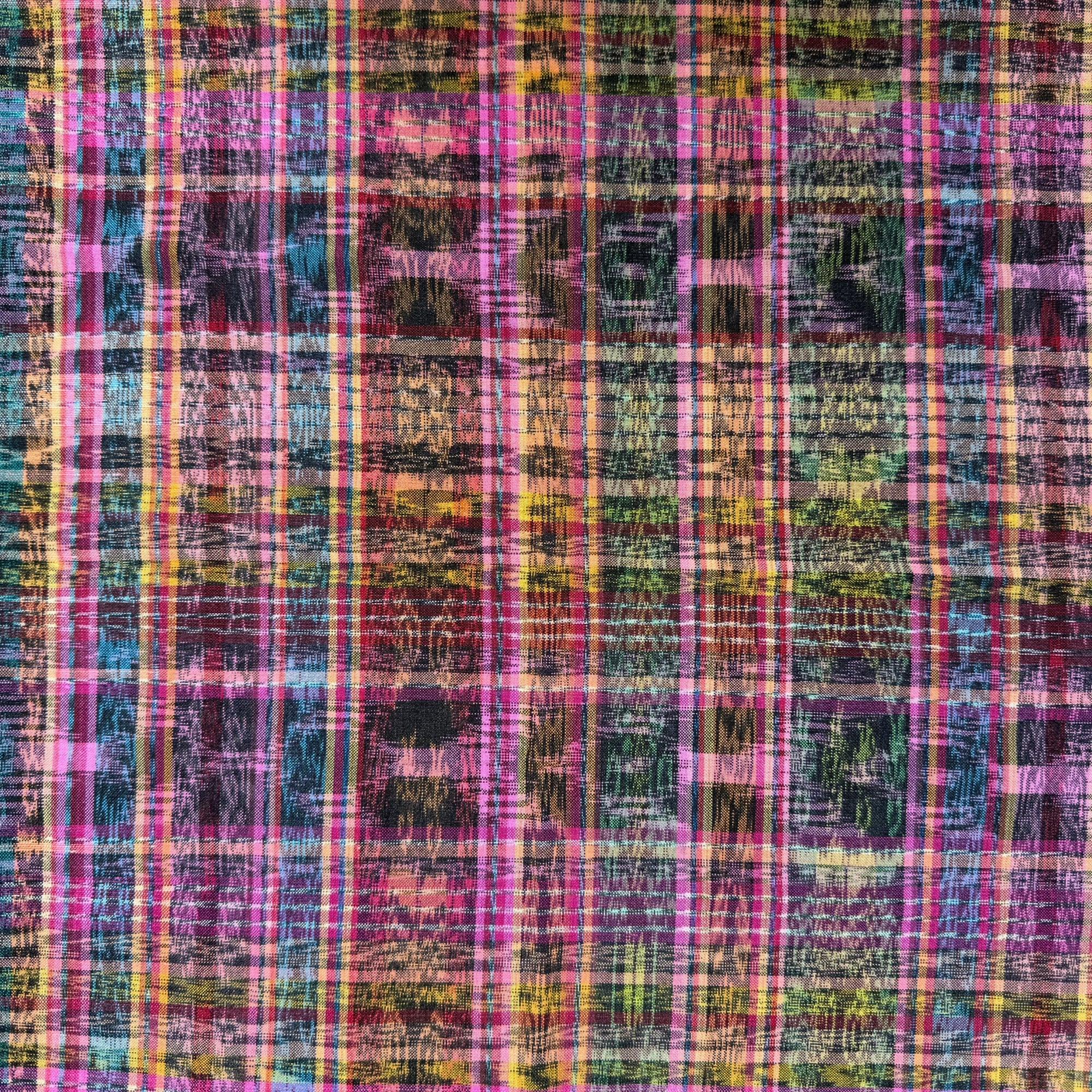 A close-up of a multicolor plaid fabric pattern with pink, purple, blue, yellow, green, and black stripes in a textured, woven look.