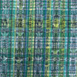 A close-up of a complex ikat plaid napkin in shades of green, blue, yellow, and white.