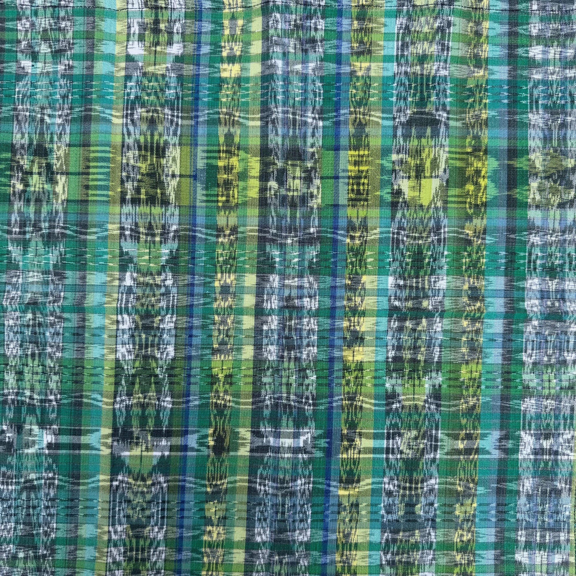 A close-up of a complex ikat plaid napkin in shades of green, blue, yellow, and white.