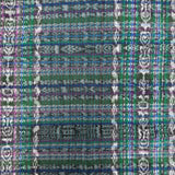 A close-up of a woven textile with a multicolor plaid and geometric pattern in green, blue, purple, white, and black.