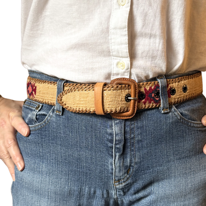 Person wearing a woven belt with floral patterns on jeans and a white shirt.