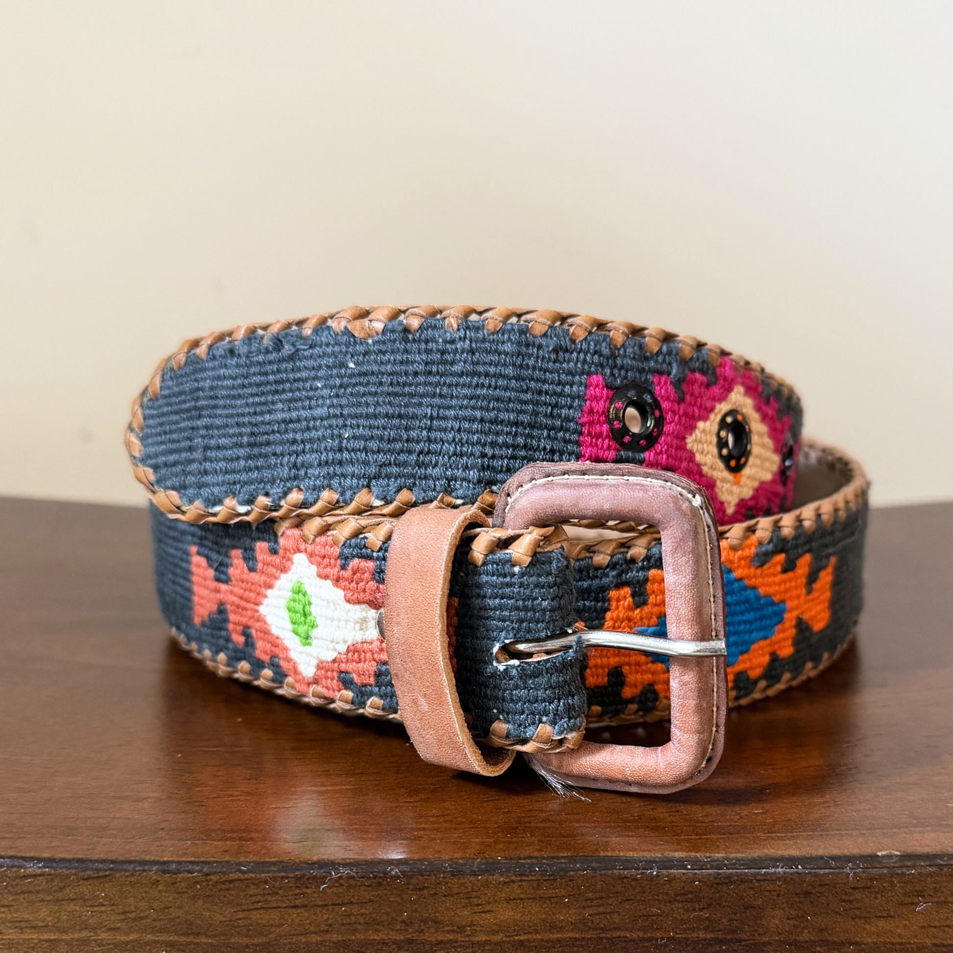 Decorative belt with floral pattern and leather buckle on a wooden surface