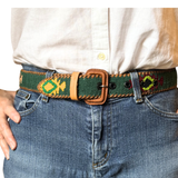 Person wearing a belt with decorative patterns on jeans and a white shirt.