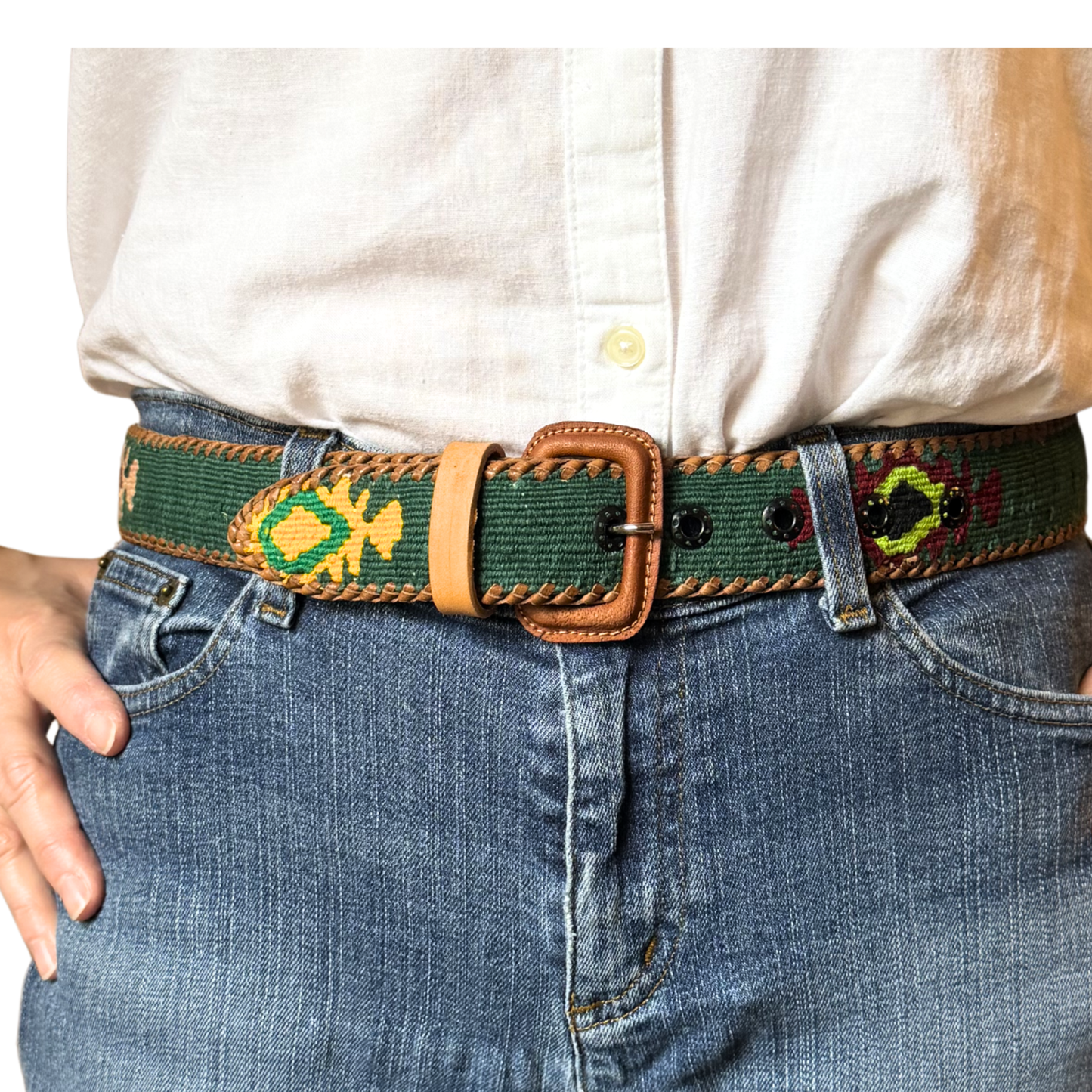 Person wearing a belt with decorative patterns on jeans and a white shirt.