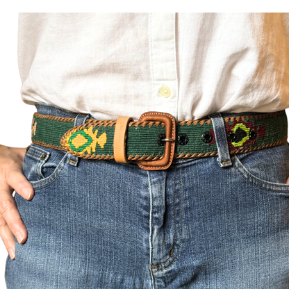Person wearing a belt with decorative patterns on jeans and a white shirt.