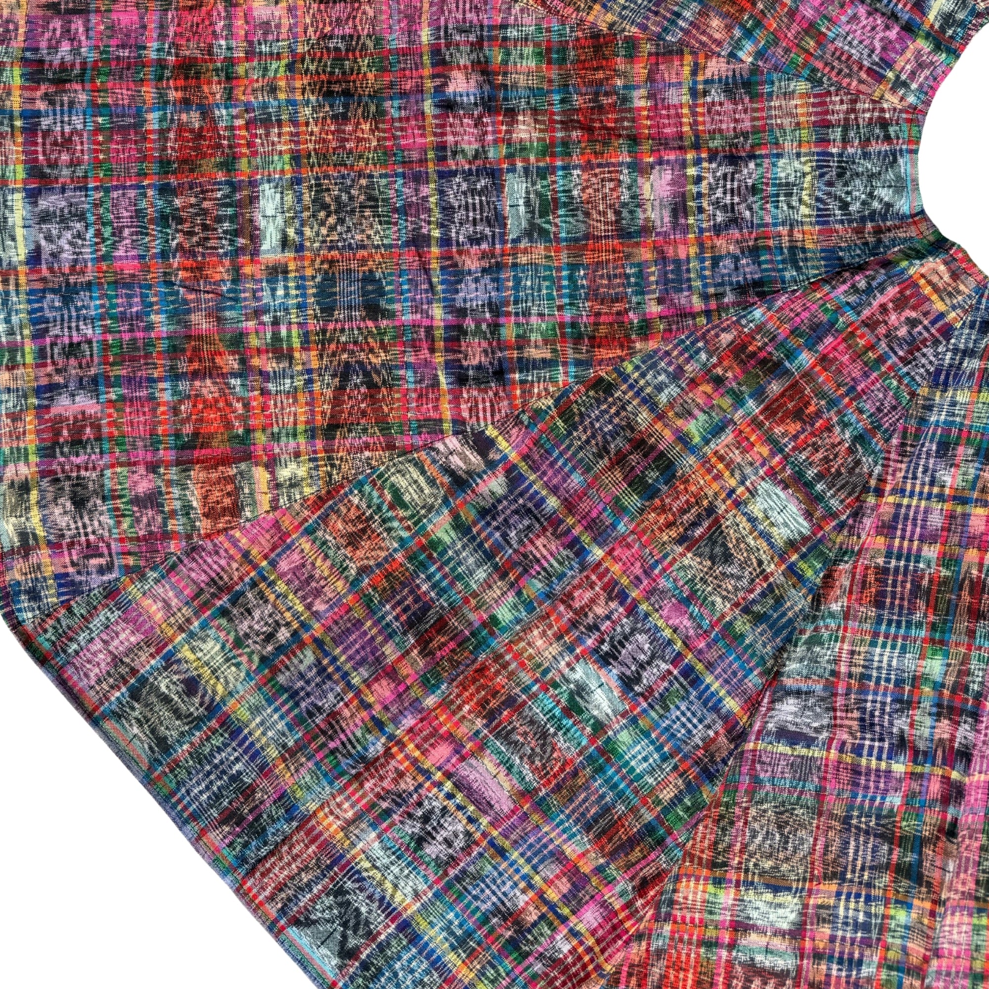 A close-up of a multicolor plaid fabric with a textured, tie-dye-like pattern in shades of pink, blue, red, orange, green, and purple, shown folded on a white background.