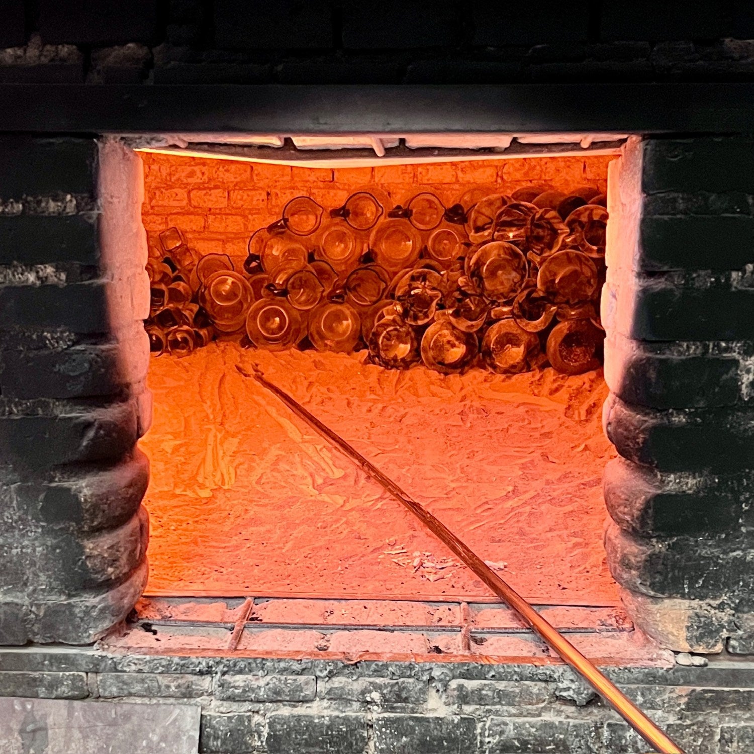 Stack of glass bottles inside a glowing furnace