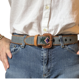 Person wearing a belt with a decorative buckle, white shirt, and blue jeans.