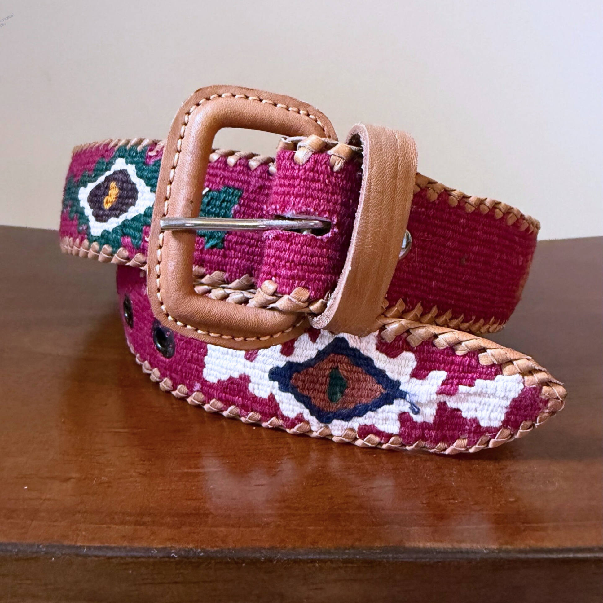 Embroidered belt with a brown buckle on a wooden surface