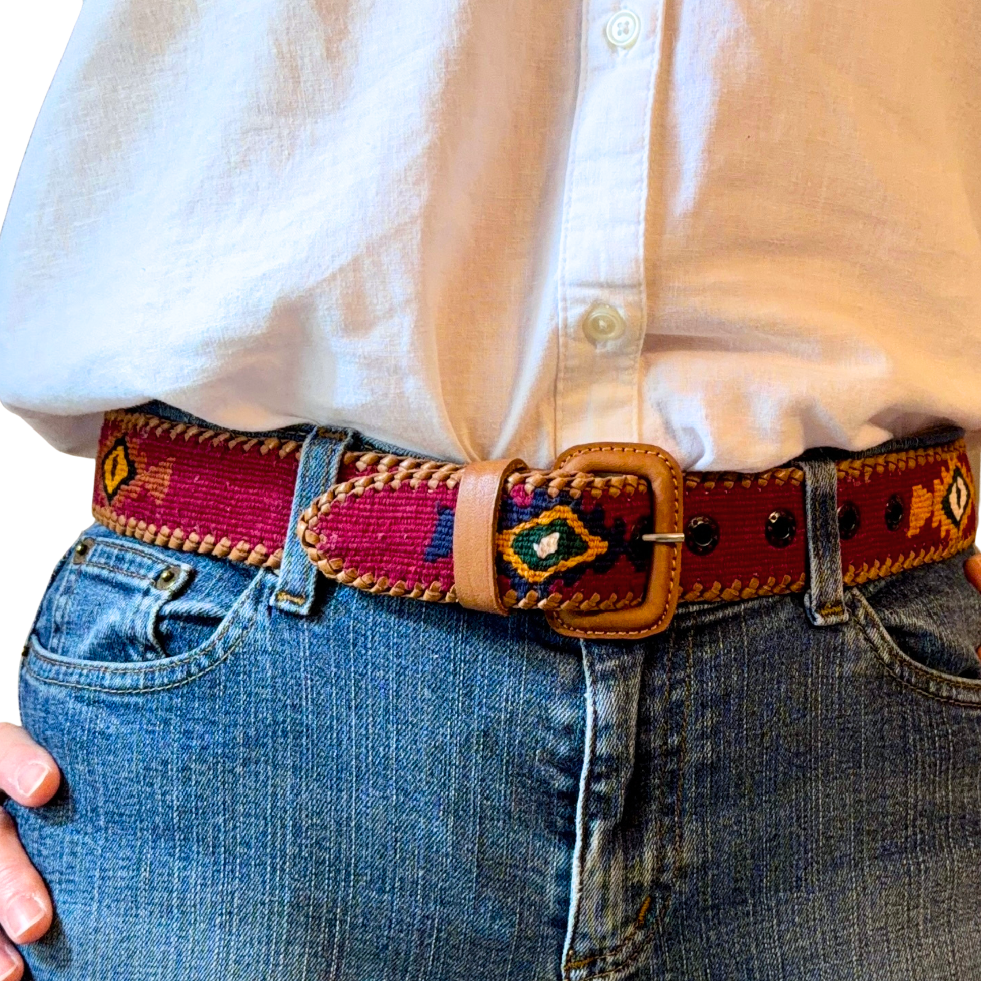 Person wearing a colorful belt with a patterned design on jeans and a white shirt.