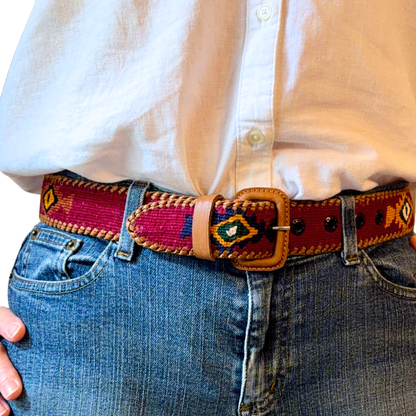Person wearing a colorful belt with a patterned design on jeans and a white shirt.