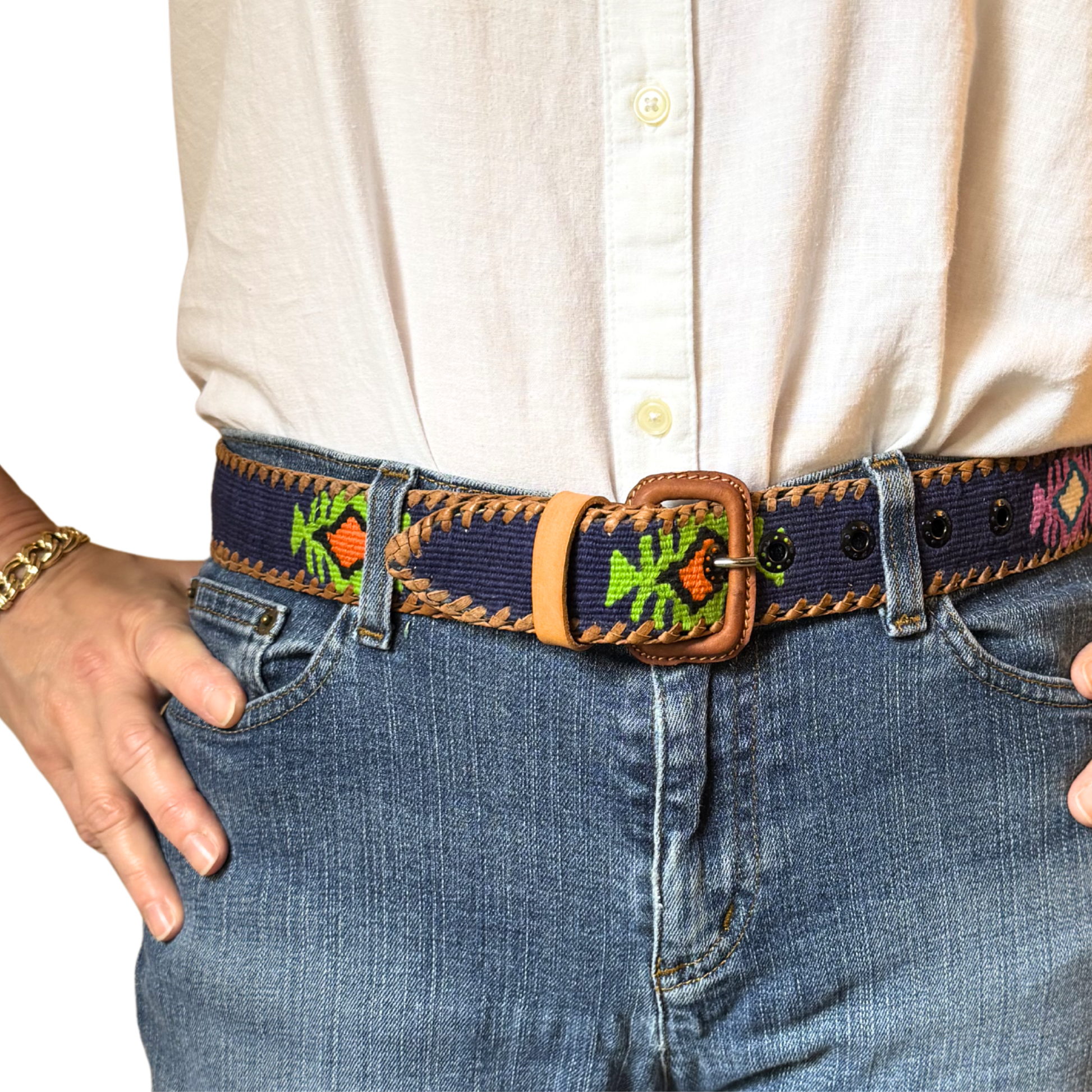 Person wearing a belt with an embroidered design on jeans and a white shirt.