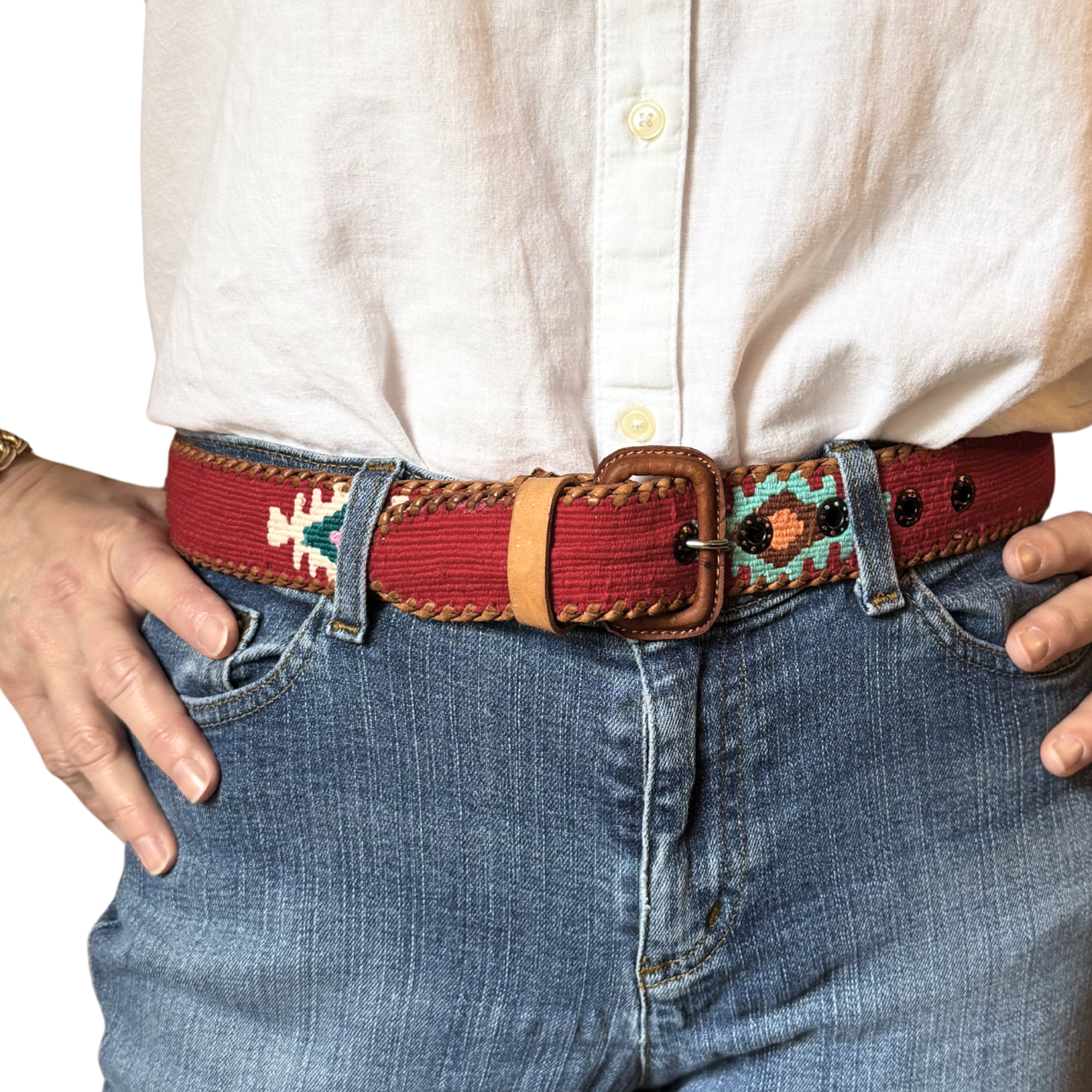 Person wearing a red patterned belt with blue jeans and a white shirt.