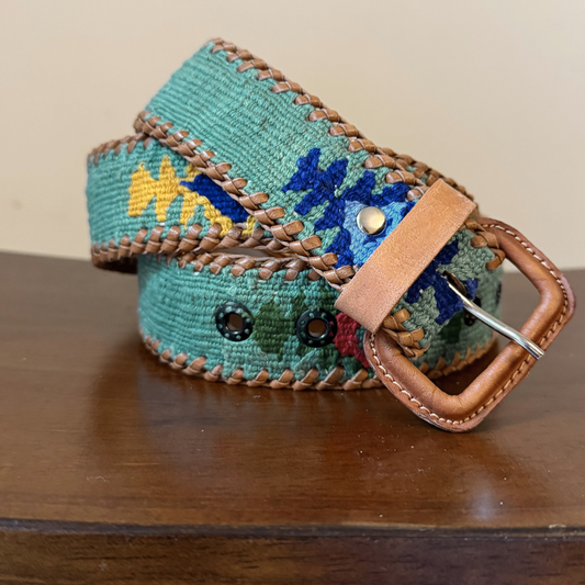 Colorful woven belt with a brown leather buckle on a wooden surface
