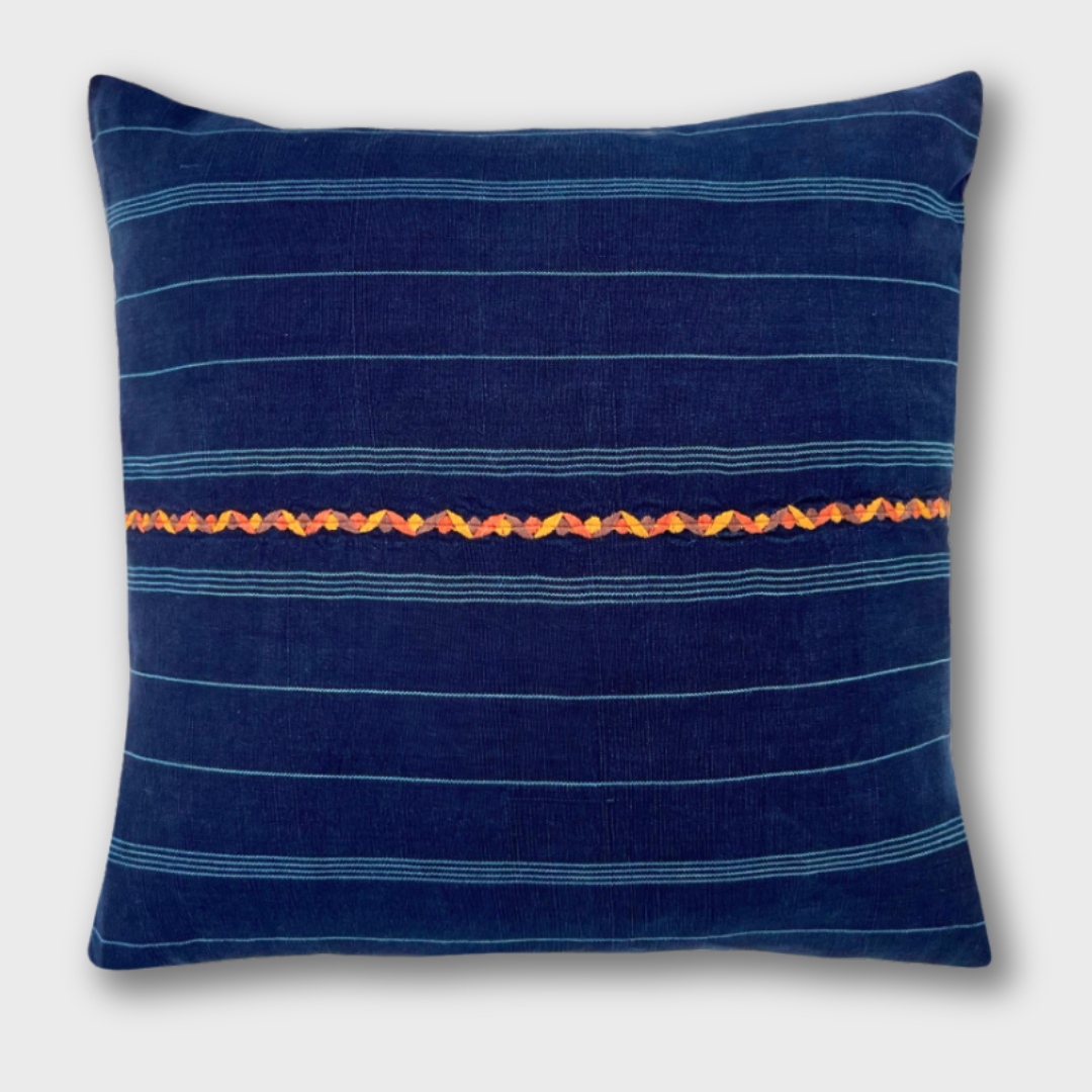 Indigo corte pillow with an orange embroidered line running horizontally across the pillow.