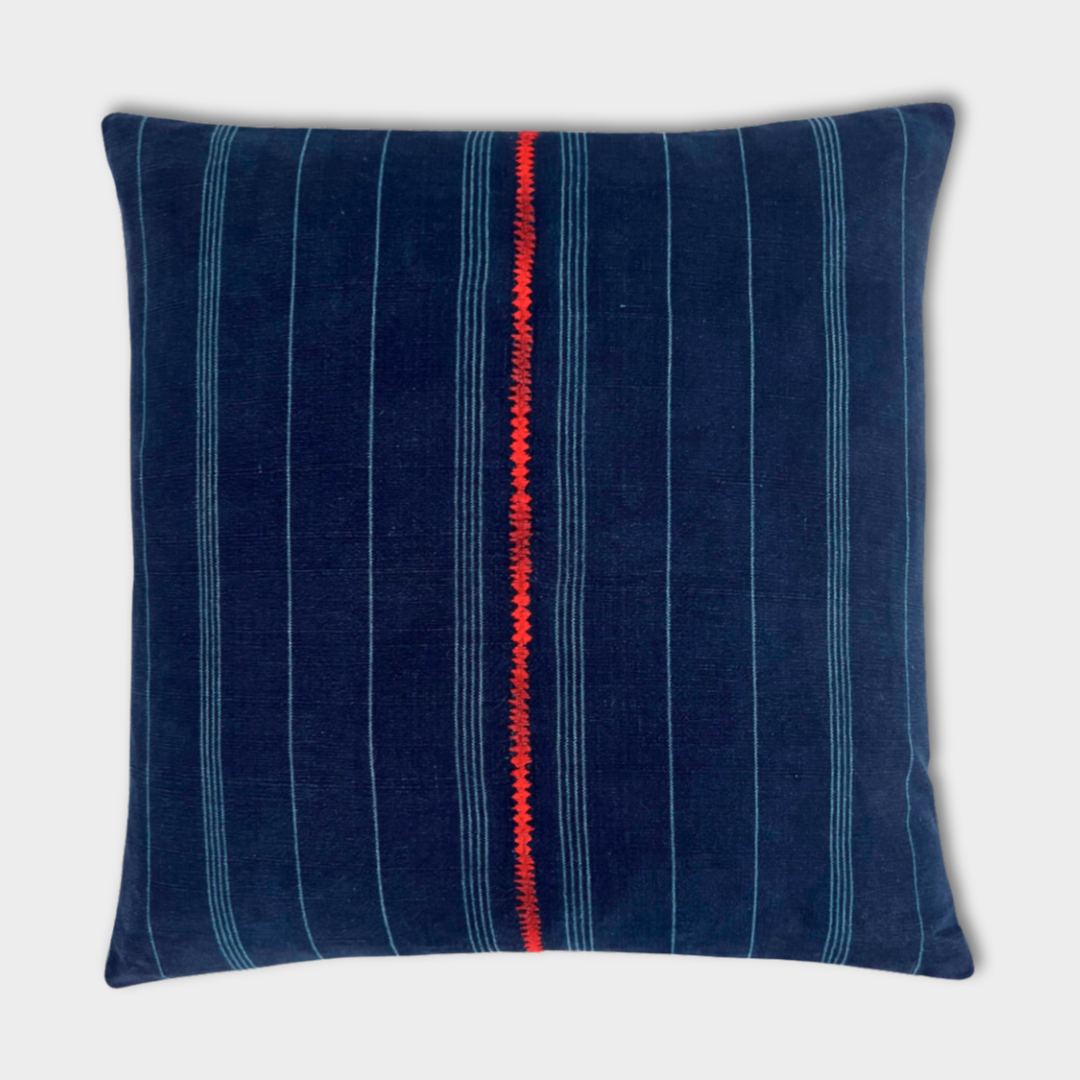 Indigo corte pillow on light gray background, with red embroidered stripe down middle. 