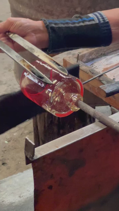 Hands holding tools to shaping mouth blown glass