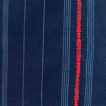 Close up of indigo corte pillow, with red embroidered stripe down middle. 